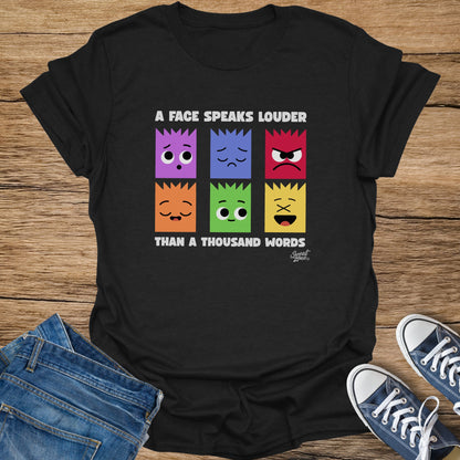 Black t-shirt with six colorful squares displaying different faces and the text "A FACE SPEAKS LOUDER THAN A THOUSAND WORDS".