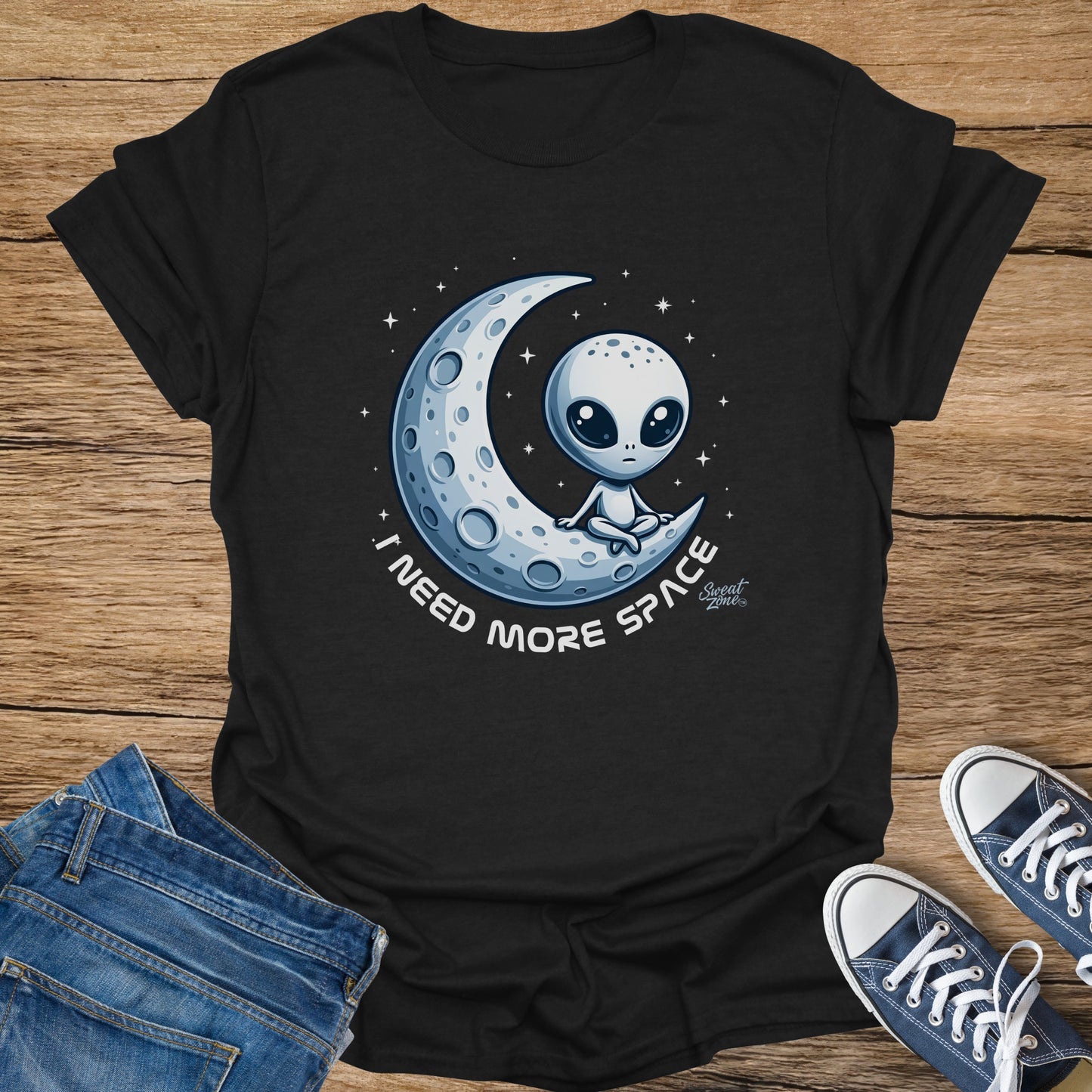 Black t-shirt with an alien sitting on a crescent moon, saying "I Need More Space."