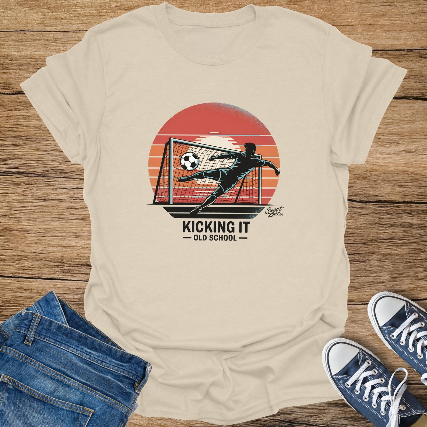 T-shirt with graphic of a soccer player kicking a ball into a net at sunset, text "Kicking It Old School".