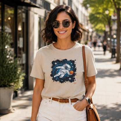 Beige t-shirt with astronaut playing basketball in space graphic on chest.