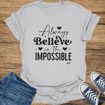 Light grey t-shirt with black text "Always Believe in the IMPOSSIBLE"