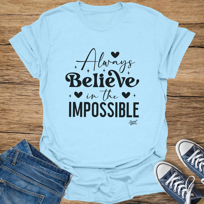Light blue t-shirt with black text "Always Believe in the Impossible".