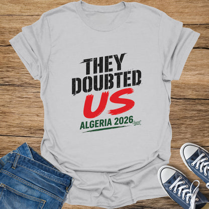 Grey t-shirt with "THEY DOUBTED US ALGERIA 2026" graphic and small logo.