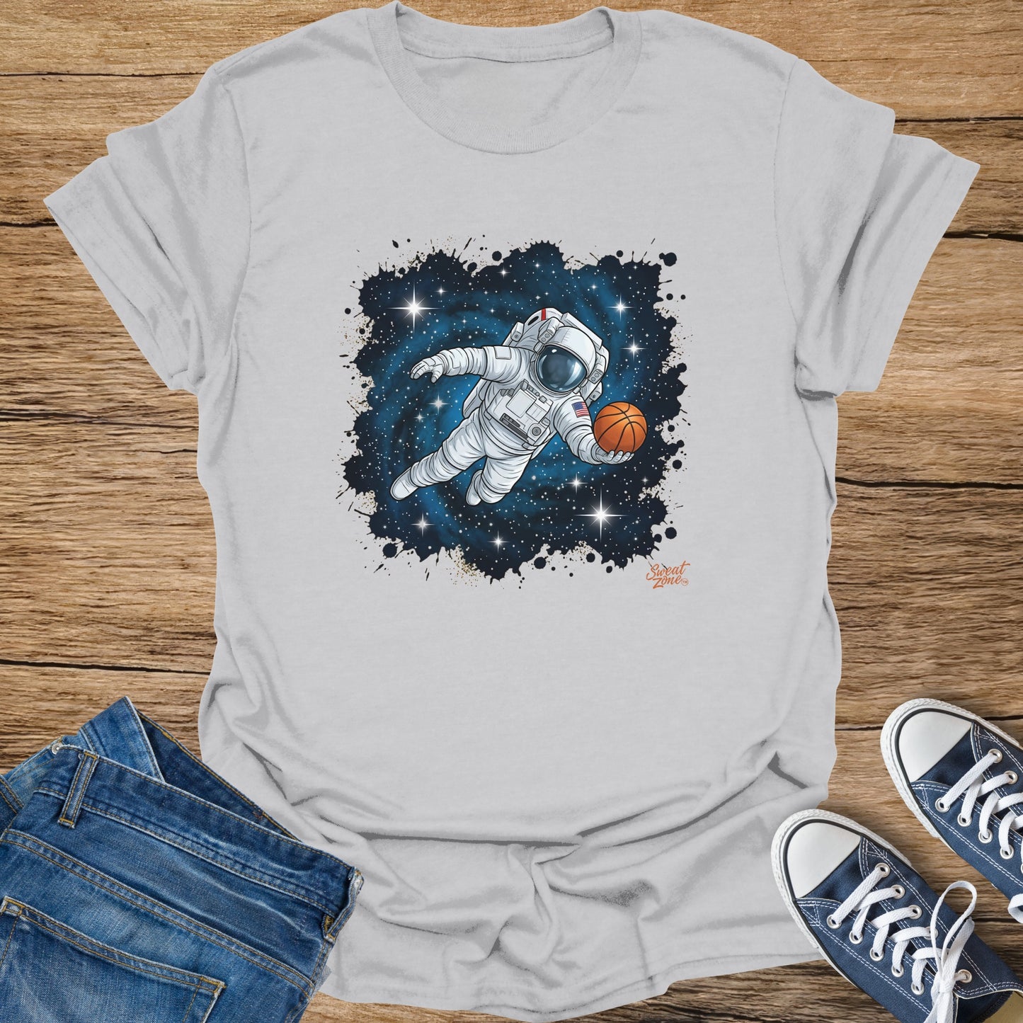 White t-shirt with astronaut playing basketball in space graphic and "Sweat Zone" logo.