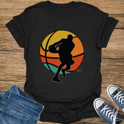 Black t-shirt with silhouette of basketball player in front of a sunset basketball design.