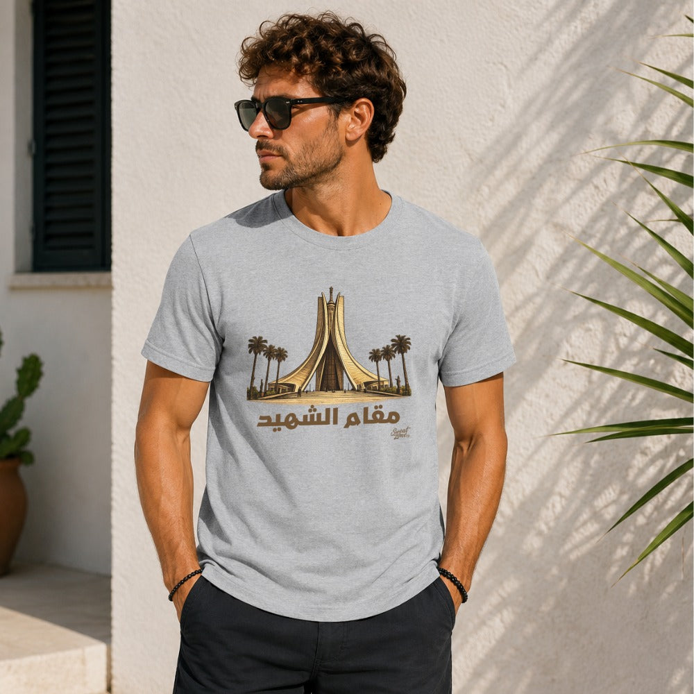 Man in light grey t-shirt with monument and Arabic text "Maqam Echahid".