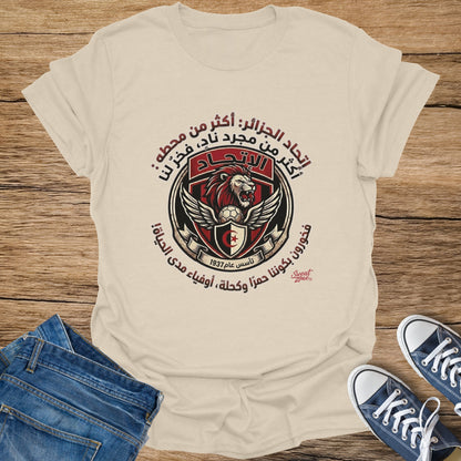 Cream t-shirt with Arabic text, lion crest, and soccer ball graphic.