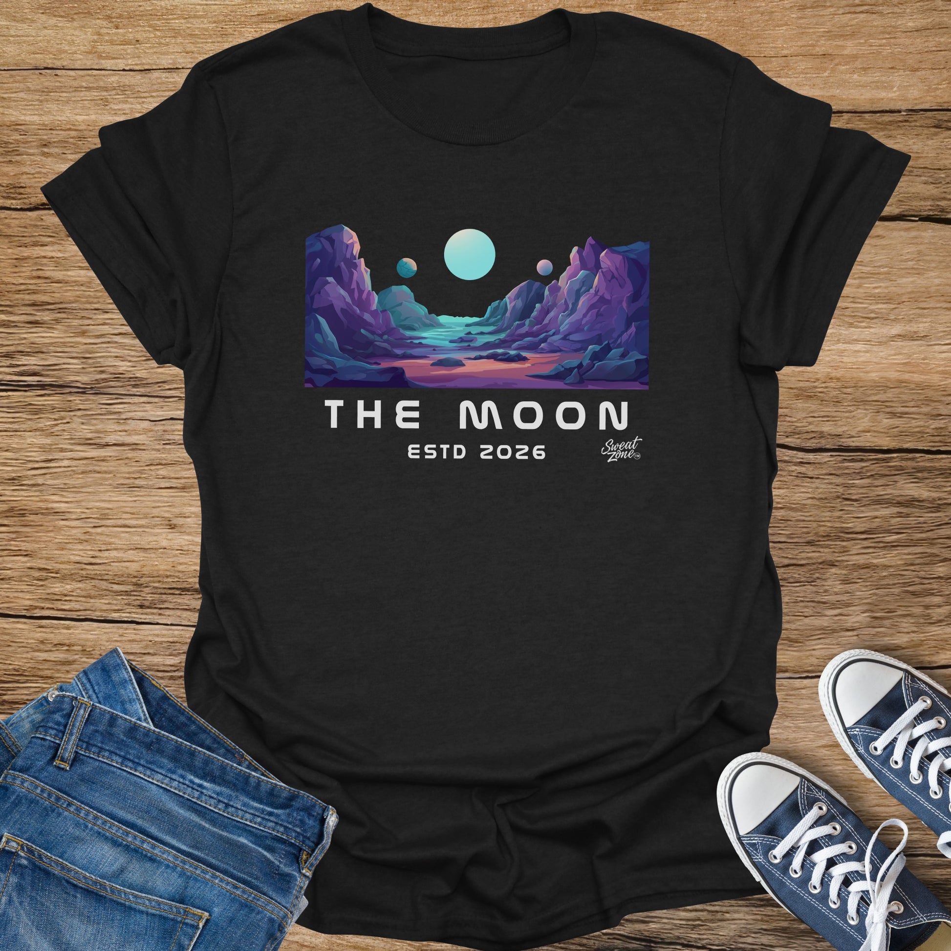 Black t-shirt with "The Moon ESTD 2026" and a colorful landscape.