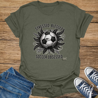 Olive t-shirt with distressed soccer balls, leaves, and text "Stressed, Blessed, Soccer Obsessed".