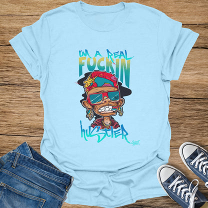 Baby blue t-shirt with cartoon of a character saying "I'm a real fuckin hustler".