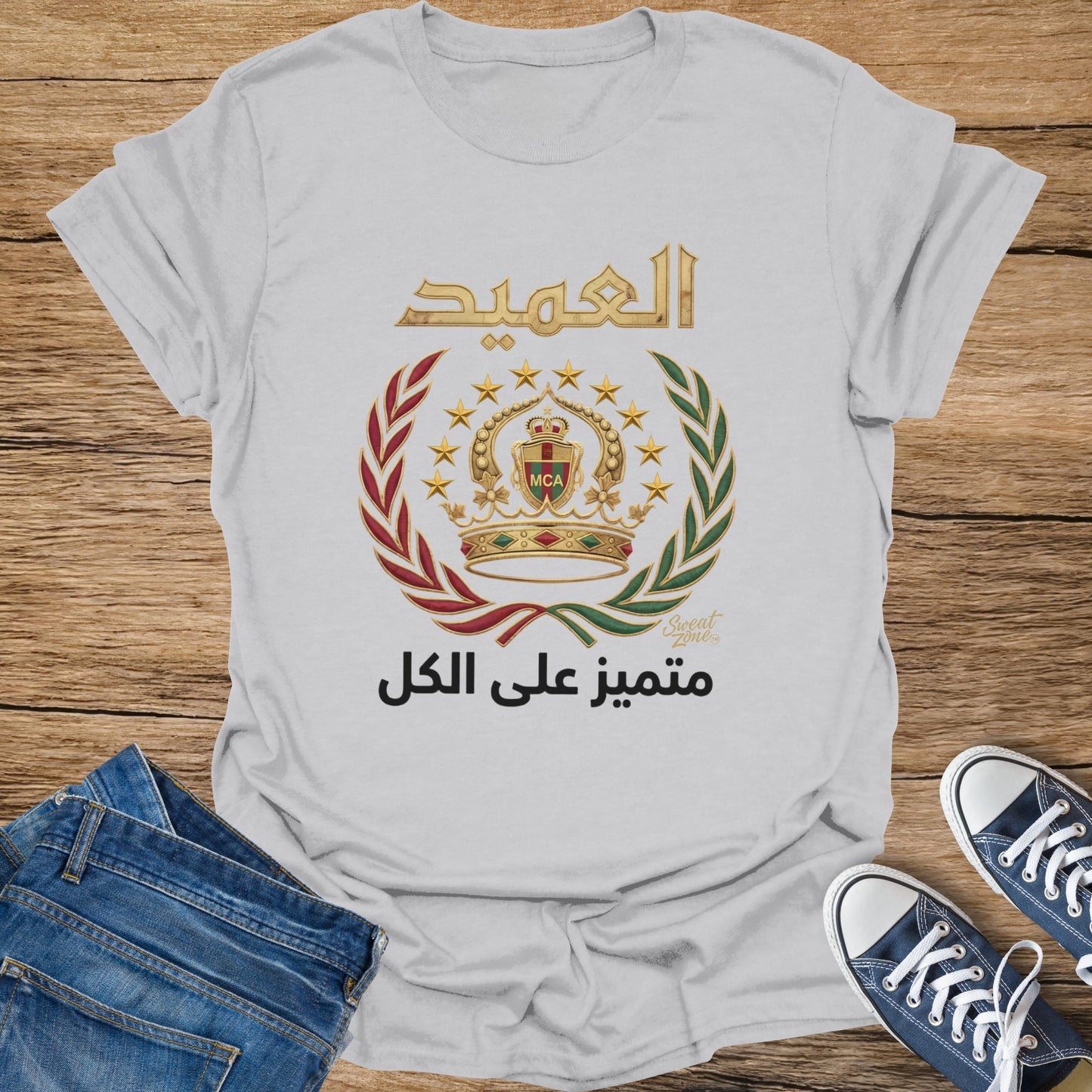 White t-shirt with Arabic text and emblem featuring crown, stars, and laurel wreath.