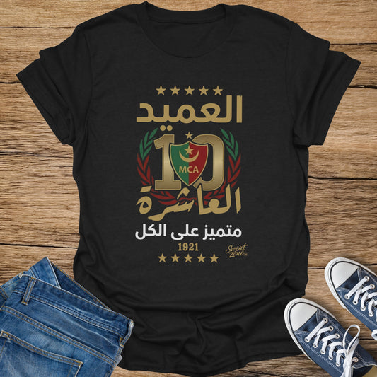 Black t-shirt with Arabic text, a large "10" with MCA logo, and stars.