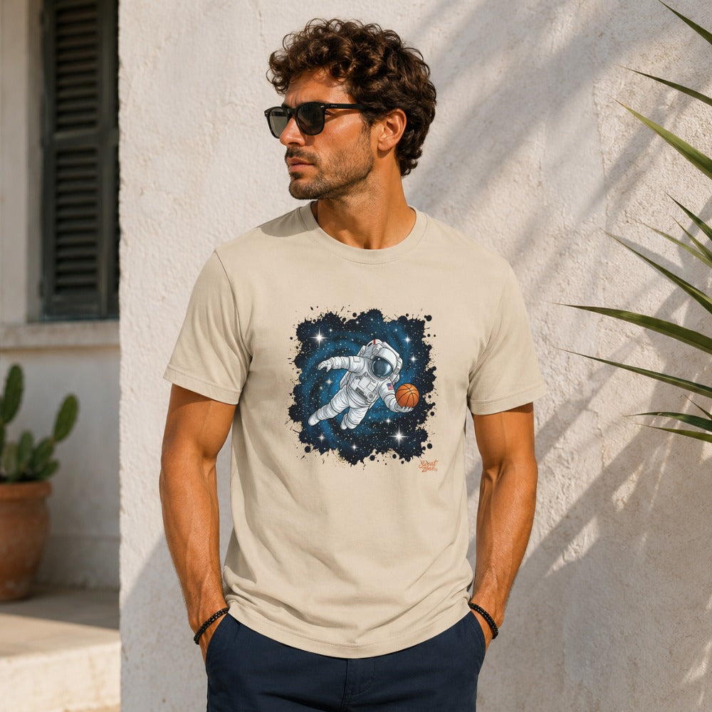 Astronaut levitating in space dribbling a basketball, graphic on a cream t-shirt.