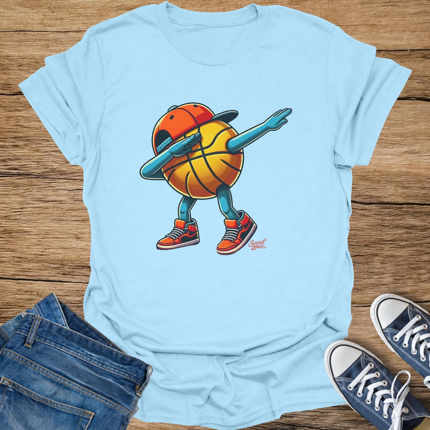 Light blue t-shirt with a cartoon basketball character dabbing, wearing a cap and sneakers.