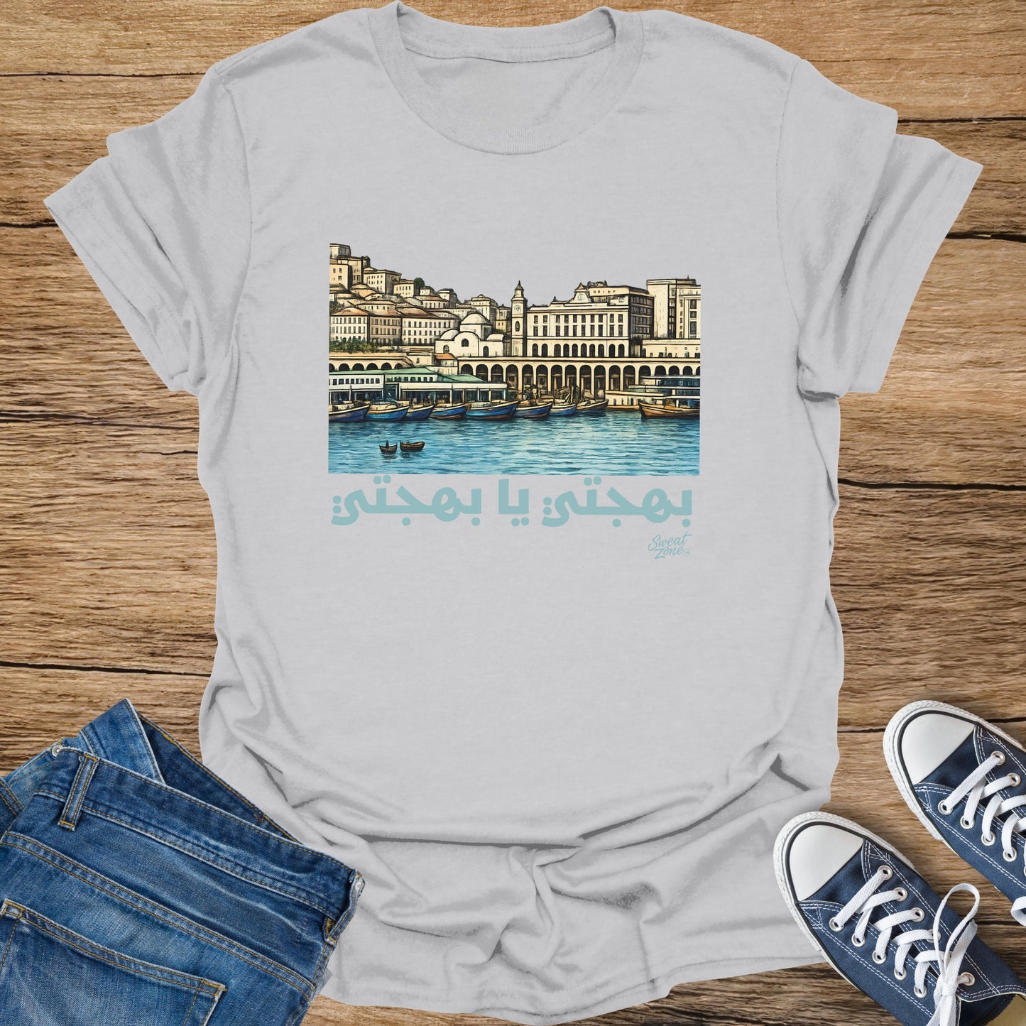 Grey t-shirt with a harbor scene in light blue and Arabic text below.