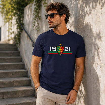 Navy t-shirt displays a shield logo with "MCA" and dates "1921" on a man.
