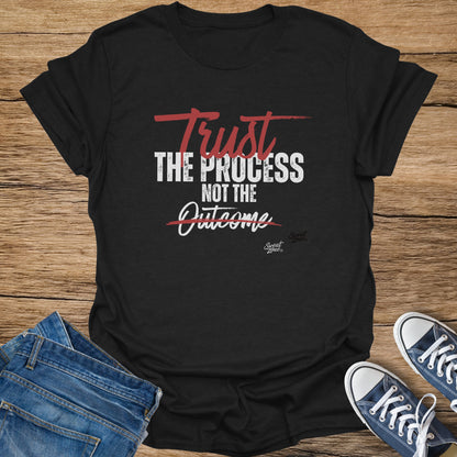 Black t-shirt with text "Trust the Process NOT the Outcome" and "Sweat Zone" logo.
