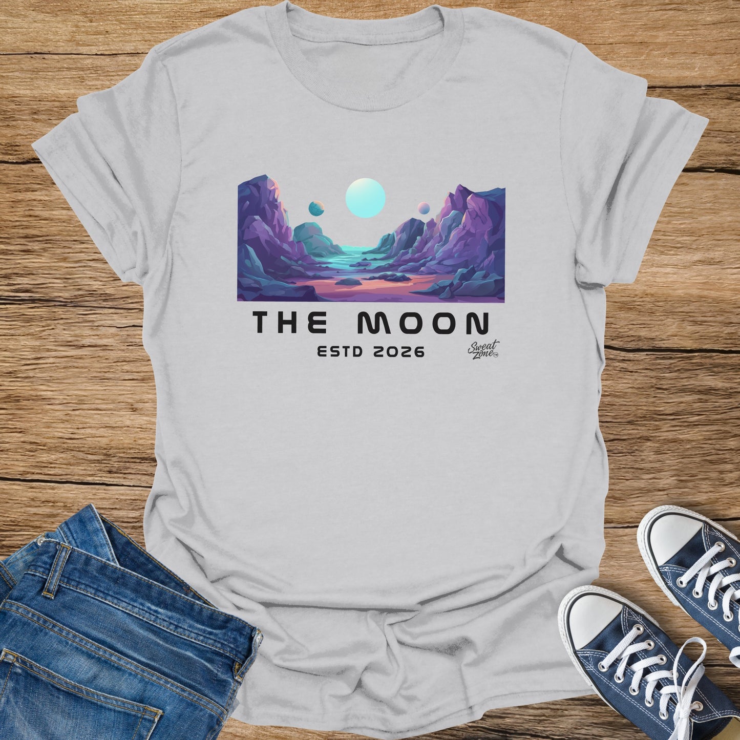 Light grey t-shirt featuring "The Moon Estd 2026" and abstract lunar landscape graphic.