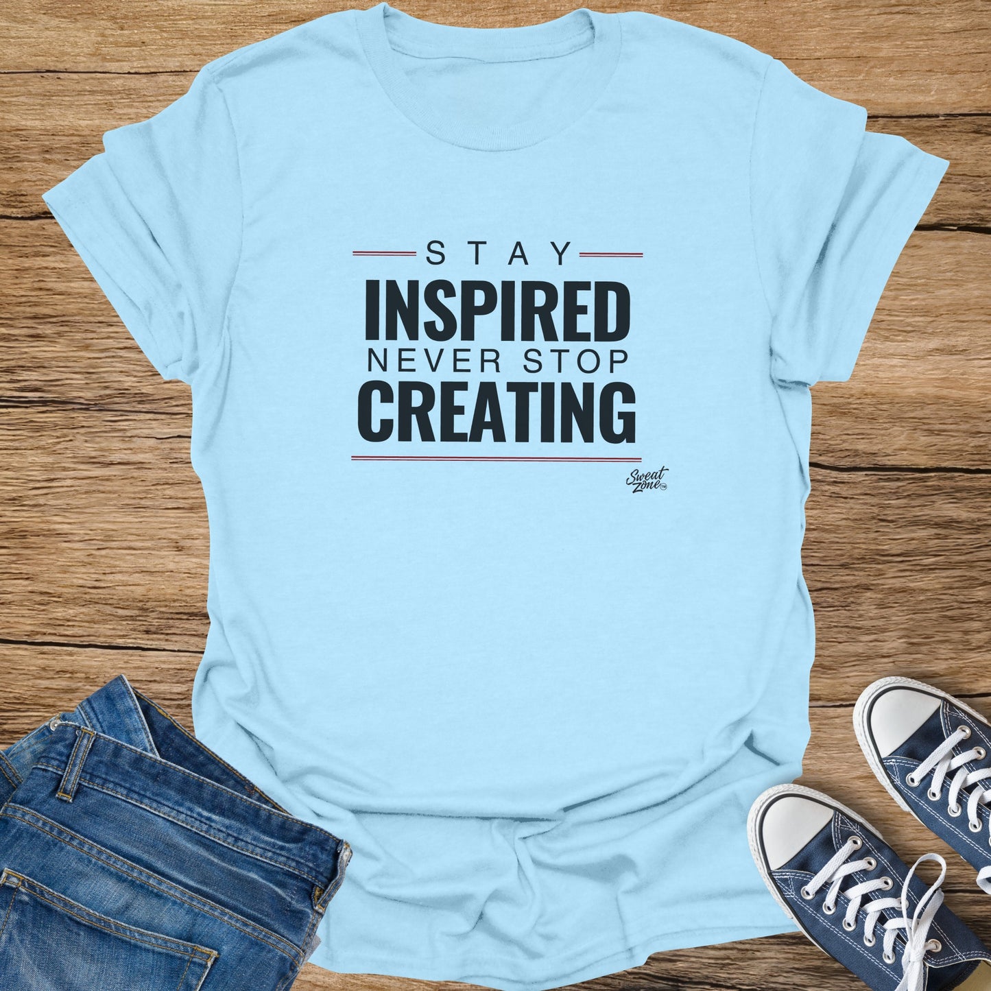 Light blue t-shirt with text "STAY INSPIRED NEVER STOP CREATING" and "Sweat Zone" logo.