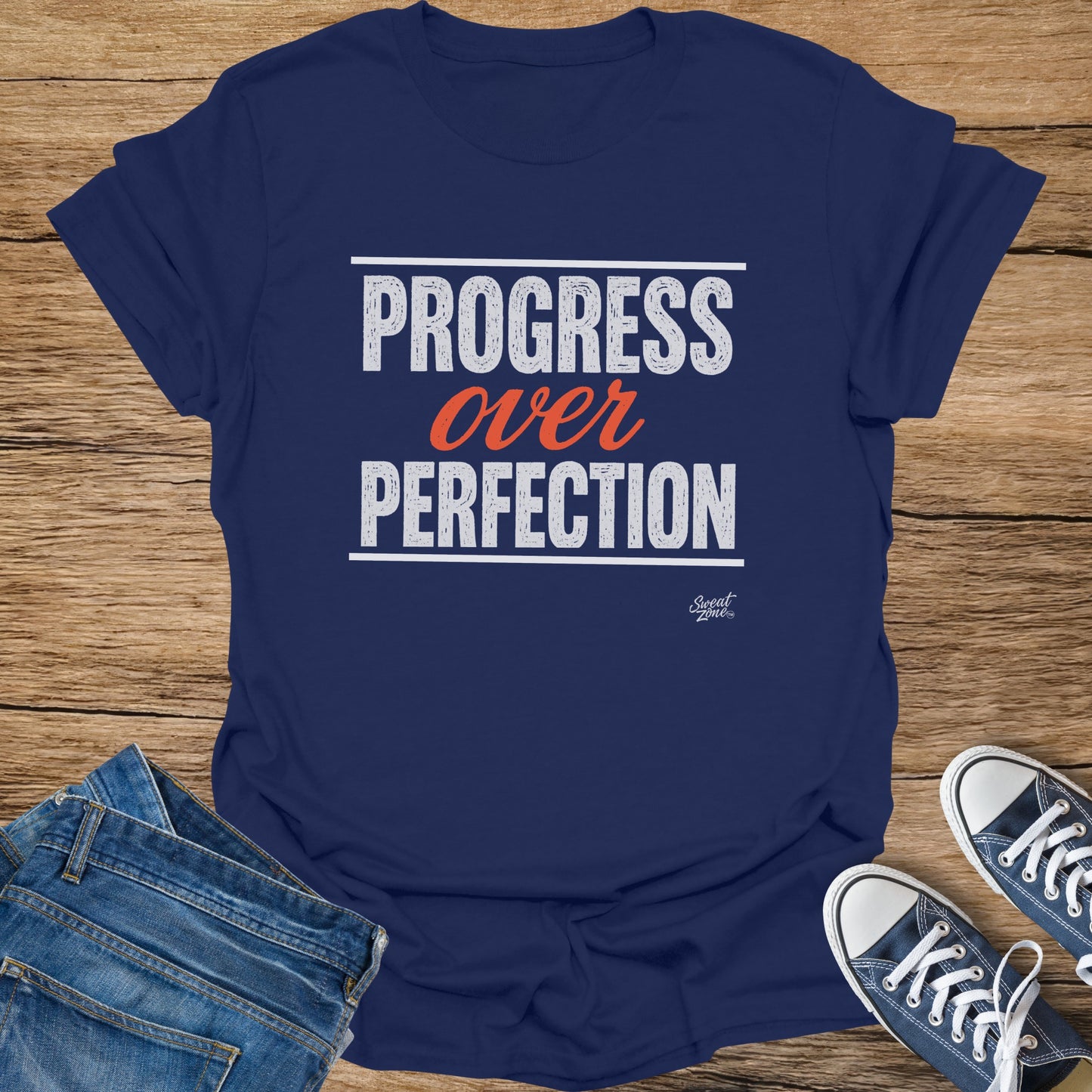 Navy t-shirt with white text "PROGRESS over PERFECTION" and small Sweat Zone logo.