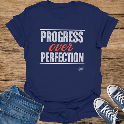 Navy t-shirt with white text "PROGRESS over PERFECTION" and small Sweat Zone logo.