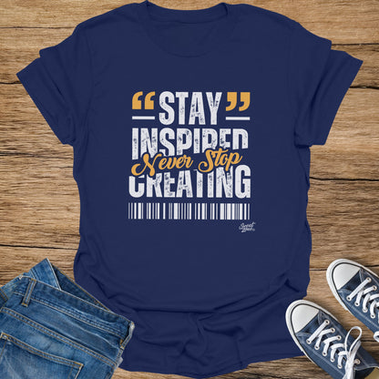 Navy t-shirt with white and orange text "STAY INSPIRED Never Stop CREATING".
