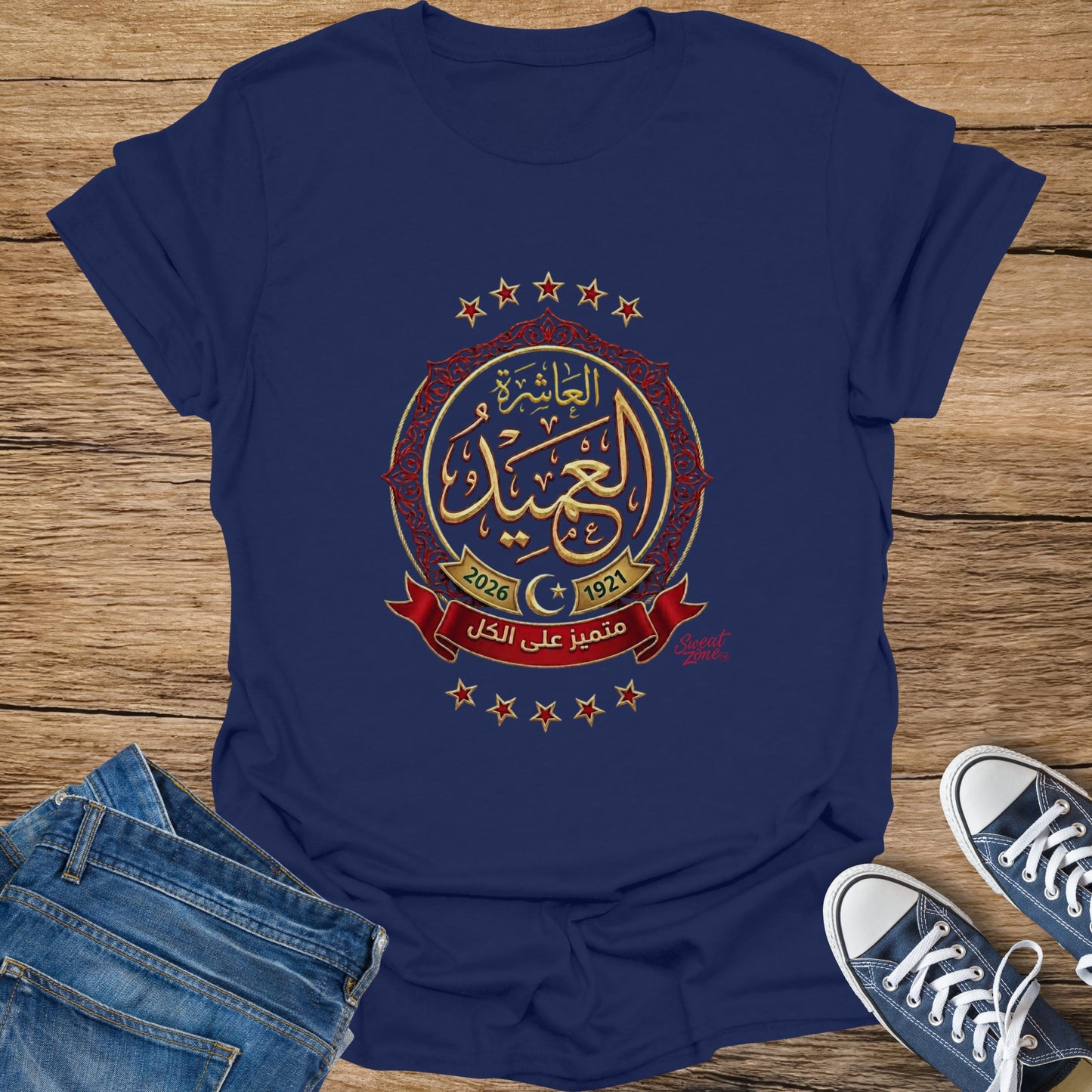 Navy t-shirt with gold Arabic calligraphy, "2026 1921", and red ribbon design.