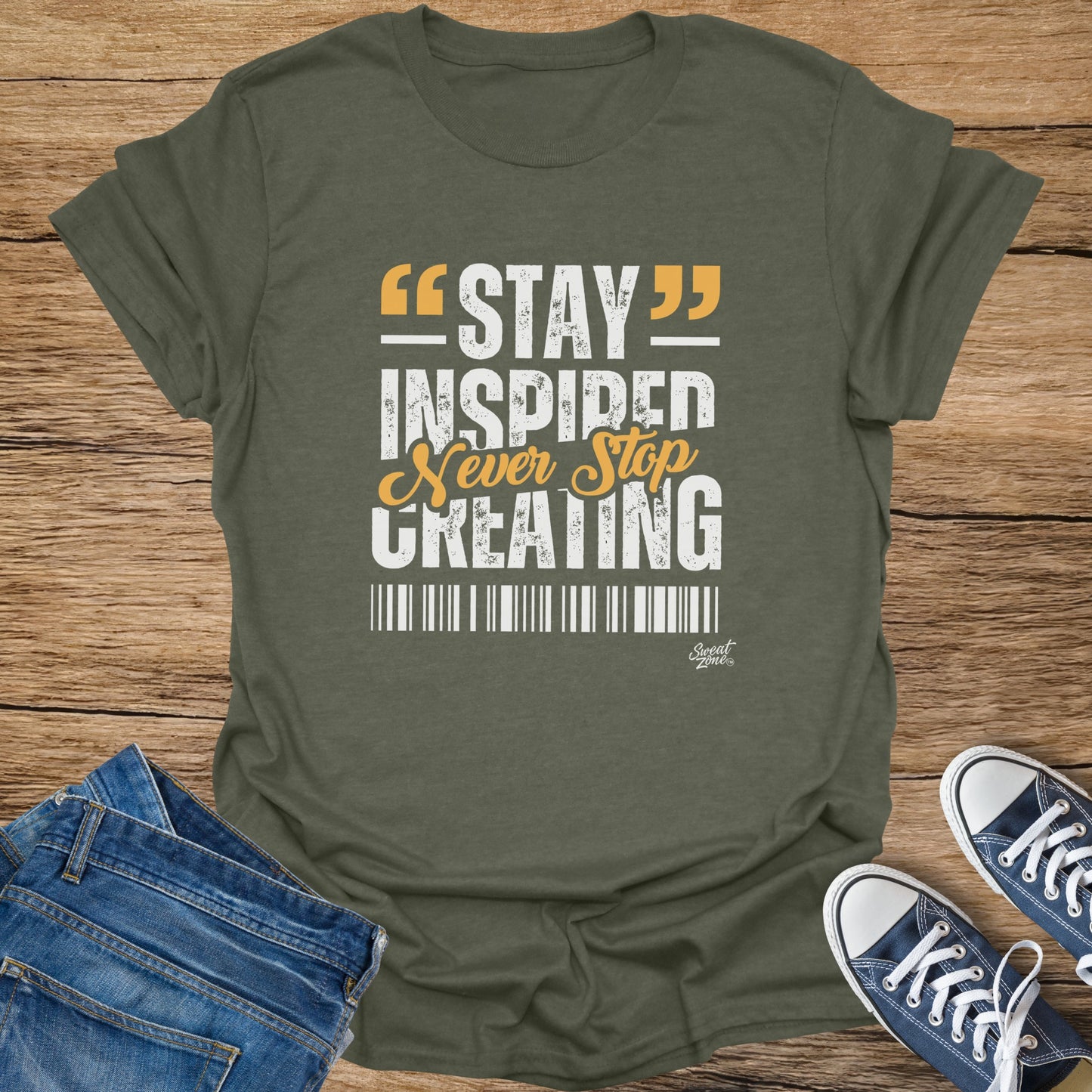 Green t-shirt with white and yellow text reading "STAY INSPIRED Never Stop CREATING".