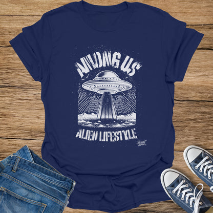 Navy t-shirt with white graphic of a UFO beaming down on mountains, reads "Among Us Alien Lifestyle".