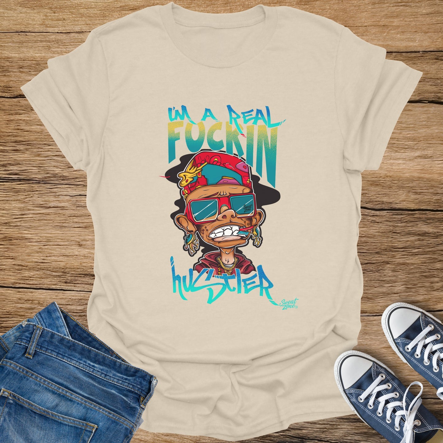 Cream t-shirt with cartoon man wearing sunglasses, hat, and jewelry with text.