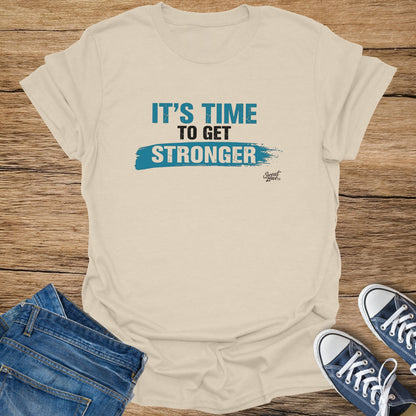 Light tan t-shirt with "It's Time To Get Stronger" text and a blue brush stroke.
