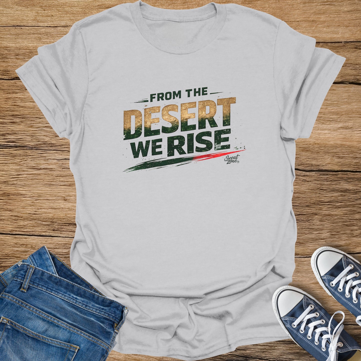 Light grey t-shirt with "FROM THE DESERT WE RISE" text and sneakers on a wooden surface.
