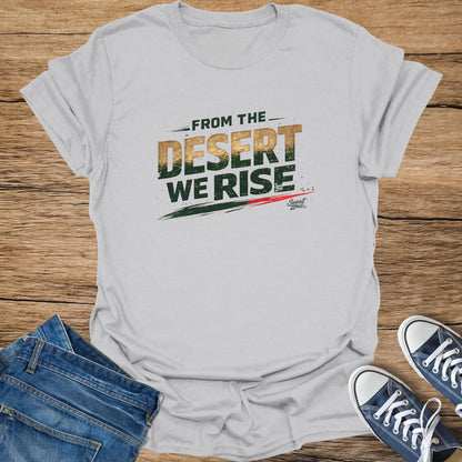 Light grey t-shirt with "FROM THE DESERT WE RISE" text and sneakers on a wooden surface.