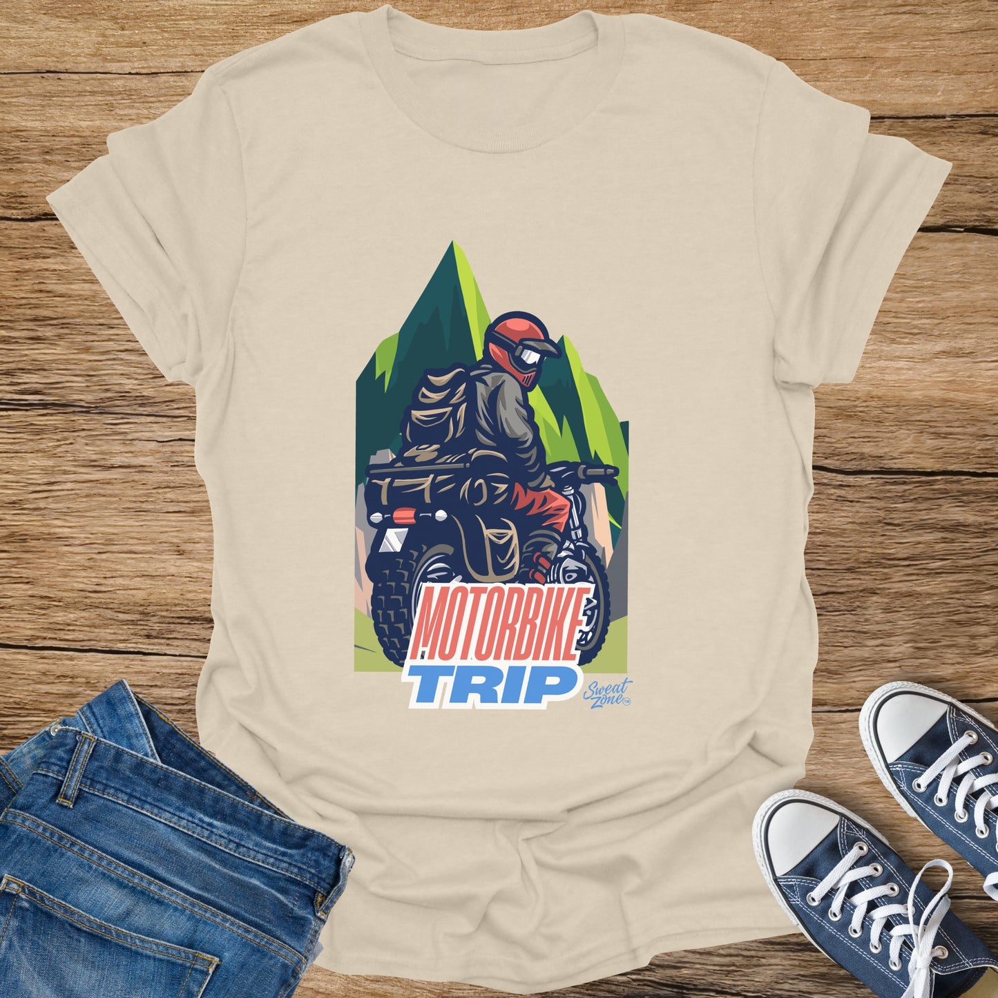Cream t-shirt with "MOTORBIKE TRIP" graphic featuring a person riding a motorbike through mountains.