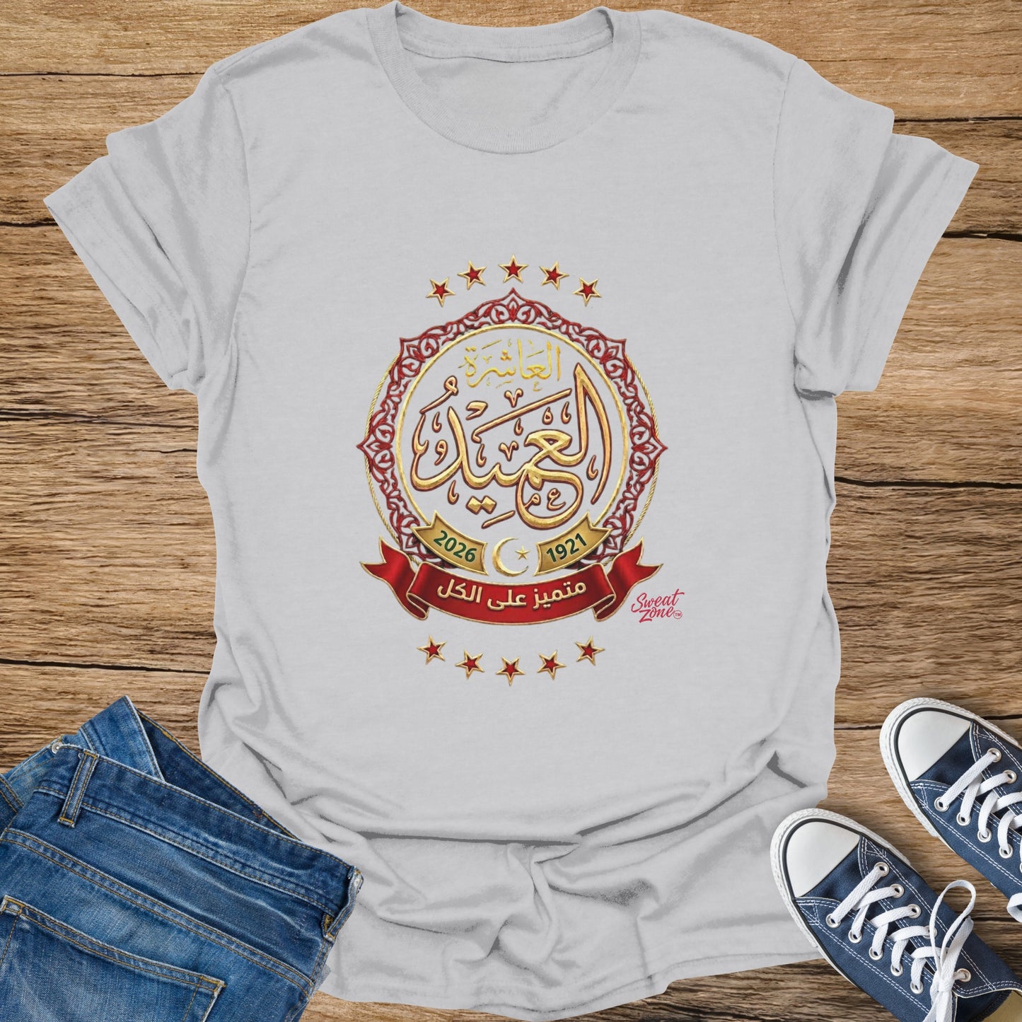 Gray t-shirt with Arabic text and gold emblem featuring stars and dates.