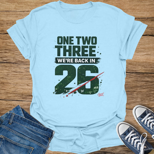 Light blue t-shirt with "ONE TWO THREE WE'RE BACK IN 26" graphic.