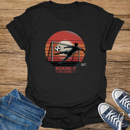 Black t-shirt with soccer player kicking ball into net under sunset. "Kicking It - Old School" text.