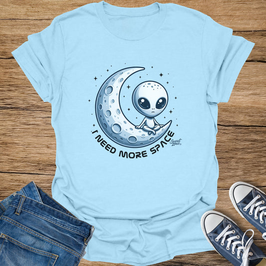 Light blue t-shirt with alien on moon graphic and text "I NEED MORE SPACE".