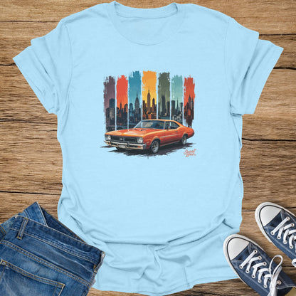 Light blue t-shirt graphic of an orange classic car and a New York City skyline.