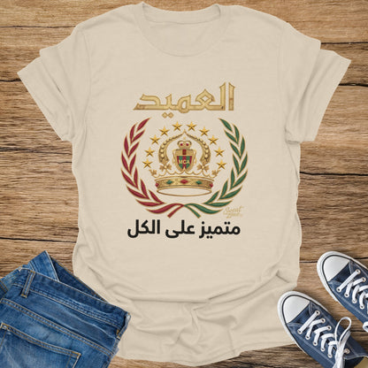 Cream t-shirt with Arabic text, crown, and laurel wreath emblem.