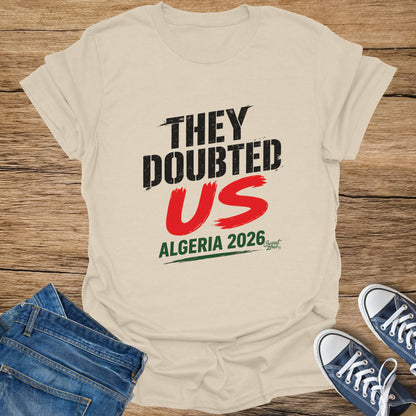 Cream t-shirt with "THEY DOUBTED US ALGERIA 2026" in black and red text.