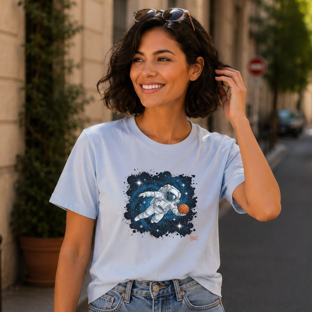 Light blue t-shirt with an astronaut dribbling a basketball in space design.