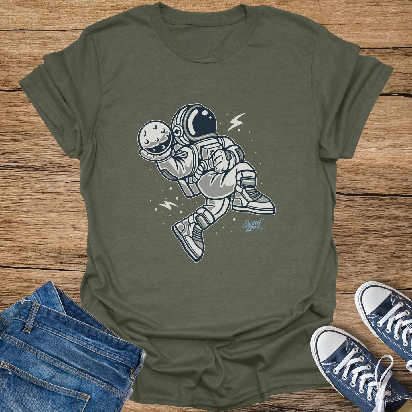 Astronaut in space suit holding moon with "Sweat Zone" logo on olive green shirt.