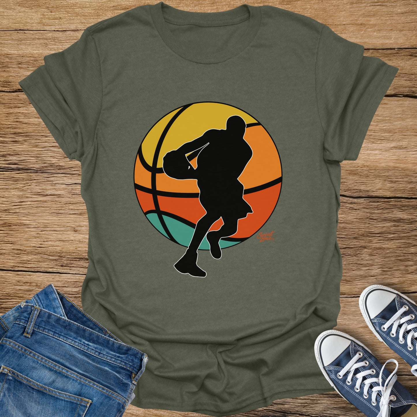 Olive green t-shirt with black graphic of basketball player and colorful sunset background.
