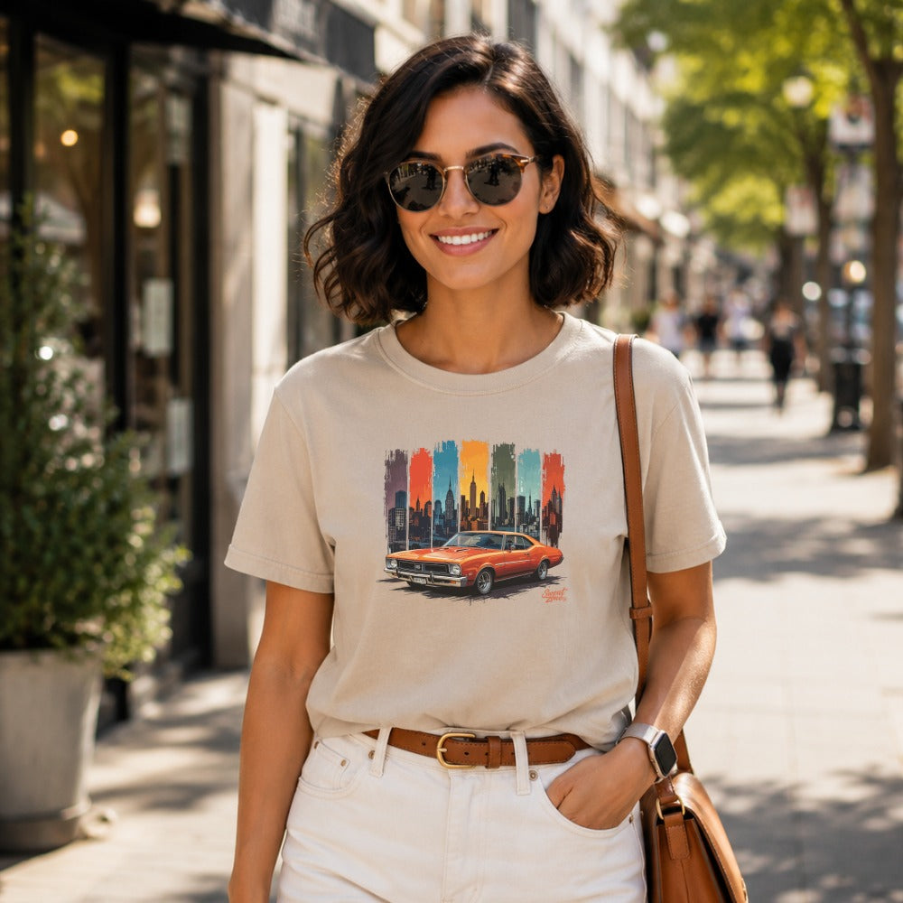 T-shirt features orange classic car graphic against a cityscape backdrop.