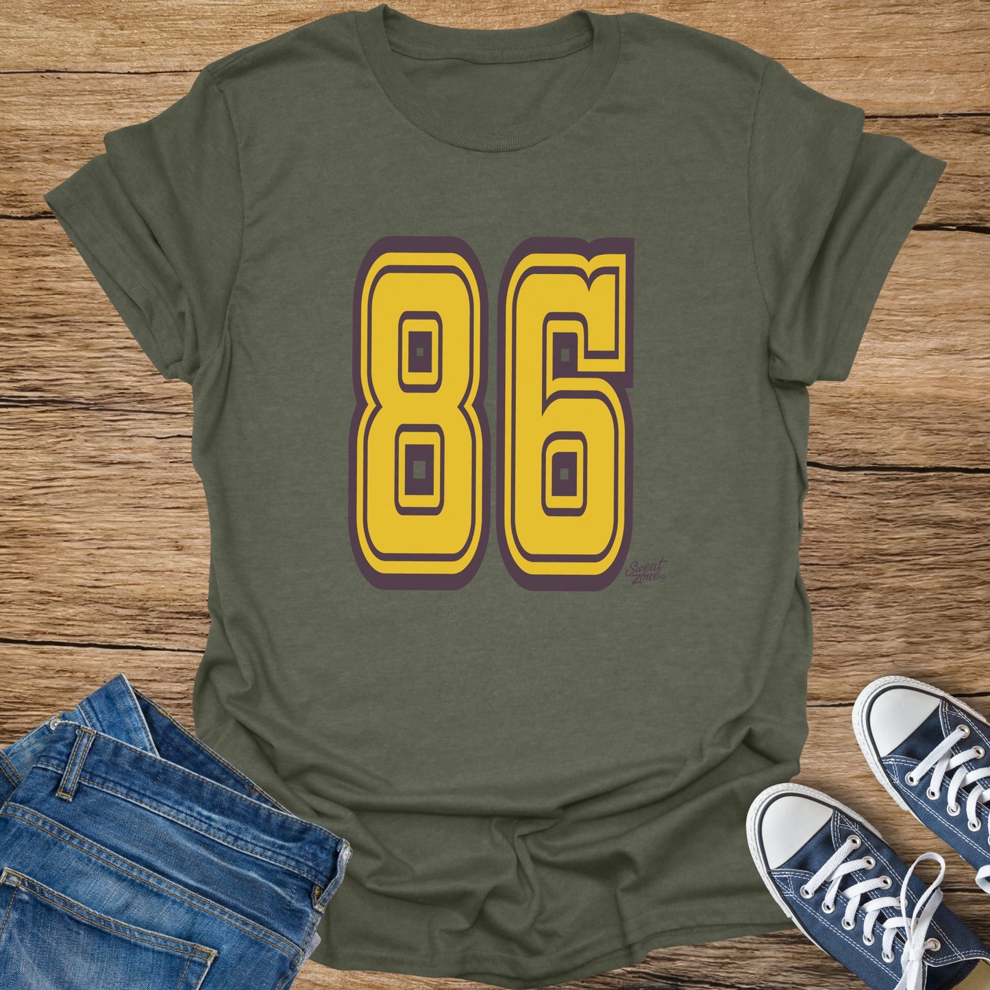 Olive t-shirt with large yellow numbers "86" outlined in purple.