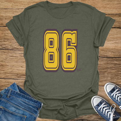 Olive t-shirt with large yellow numbers "86" outlined in purple.