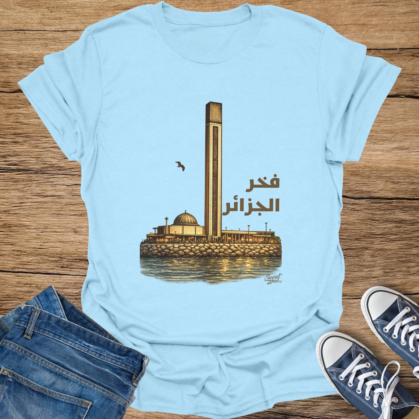 Light blue t-shirt with graphic of Djamaa el Djazaïr and Arabic text "Fahr al-Jazair".