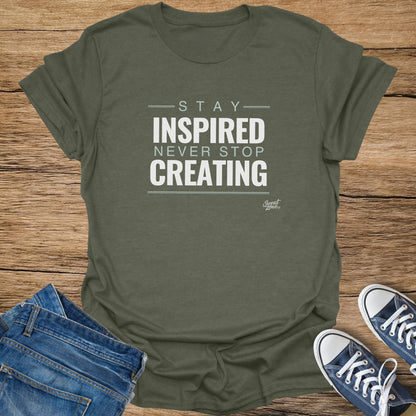 Olive green t-shirt with "Stay Inspired Never Stop Creating" text.
