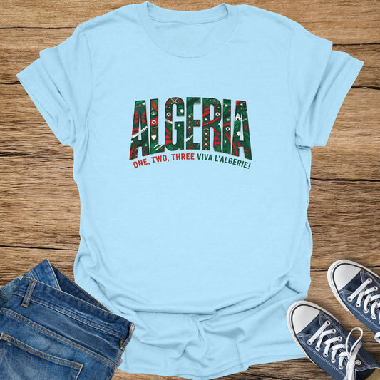 Light blue t-shirt with "ALGERIA" in green and red patterned letters, with "ONE, TWO, THREE VIVA L'ALGERIE!" below.